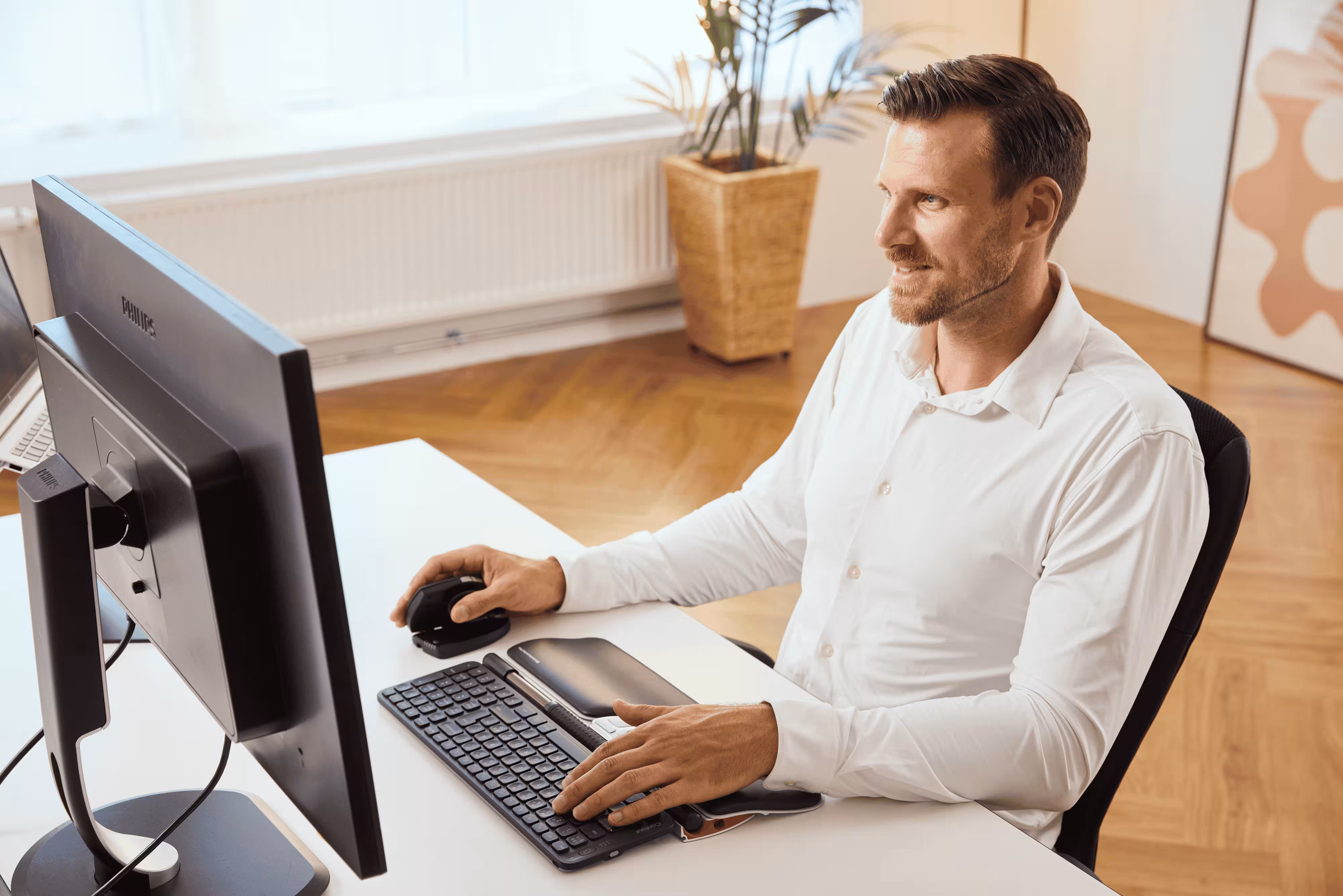 Woman stretching wrist at UK home office to relieve mouse elbow