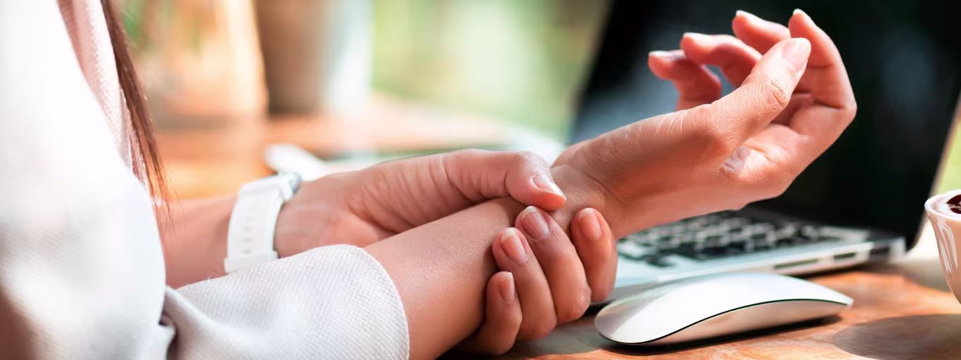 UK office worker at night rubbing numb ring and little fingers.