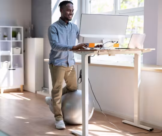 Height-adjustable standing desk with monitor setup, showcasing ergonomic equipment for home office productivity and movement throughout the workday.