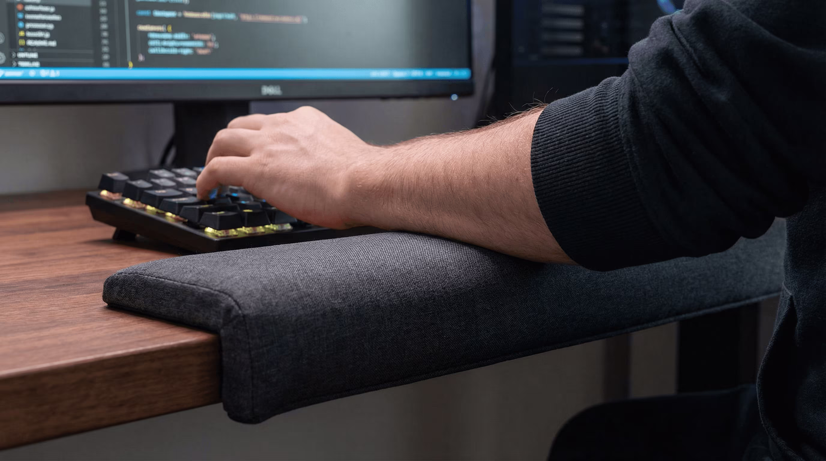 Unterarm ruht auf einem langen Tischkanten-Pad für ergonomische Ellbogenstütze.