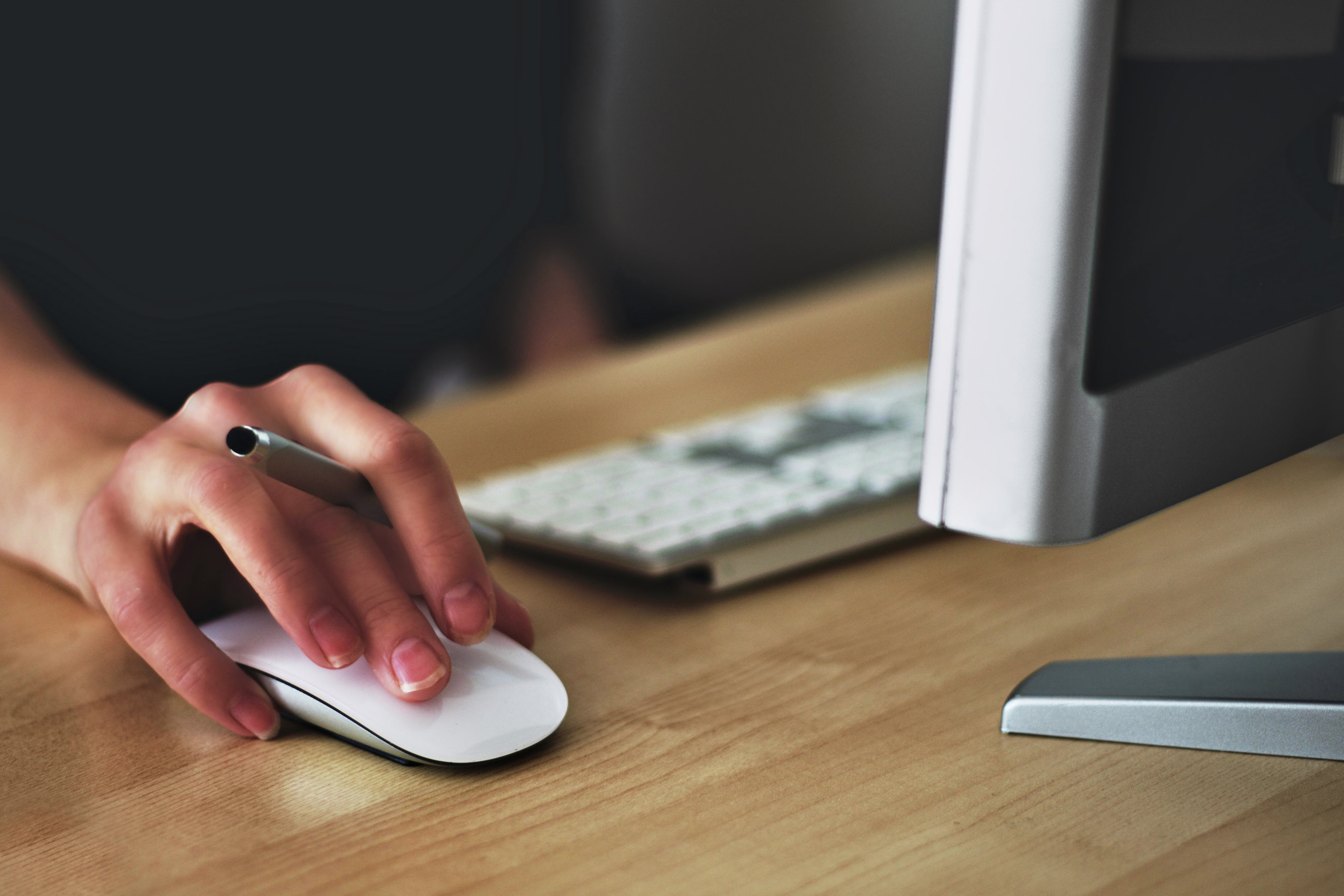 Close-up of a hand using a computer mouse at a desk, illustrating a workstation habit that can contribute to pain in the thumb joint.