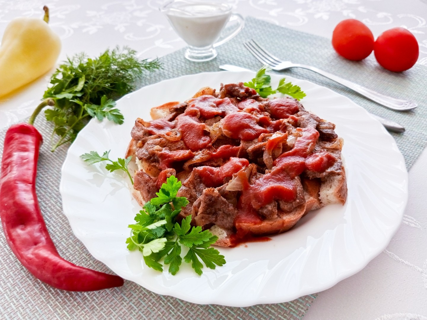 Iskender kebab on a scalloped white plate — sliced doner-style meat and onions over bread, topped with tomato sauce and garnished with parsley