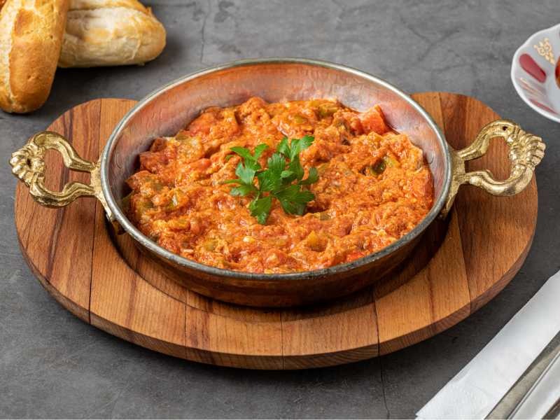 Turkish menemen scrambled eggs cooked with tomatoes and green peppers, garnished with a parsley leaf