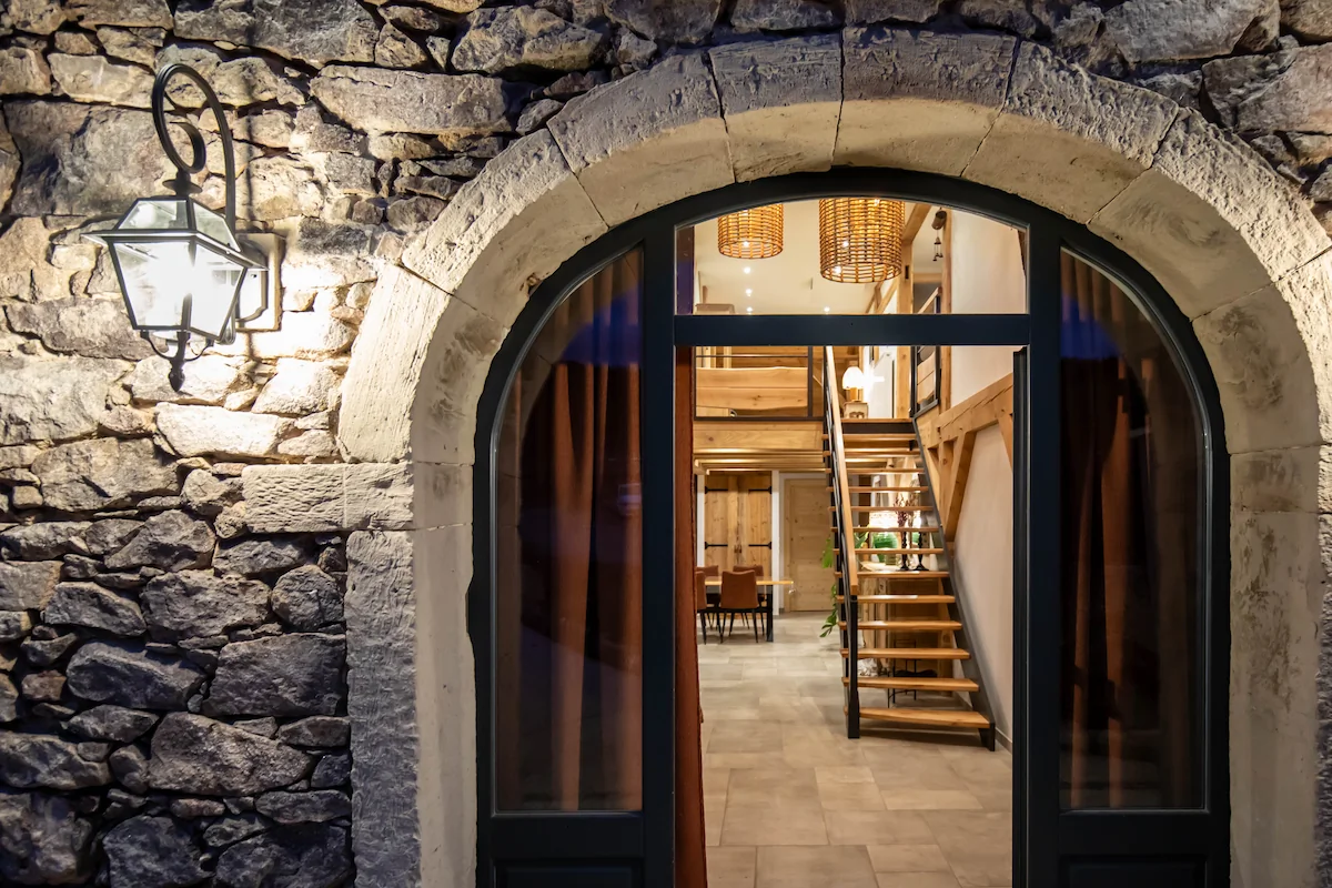 Modern restroom with wall-mounted toilet, small sink, and gray tiled walls and floor.
