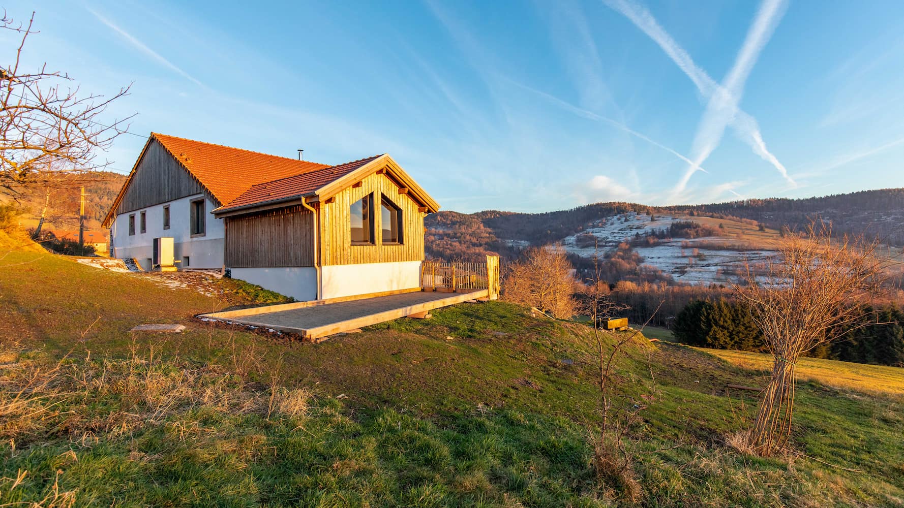 Modern bathroom with black marble walls, walk-in shower, wall-mounted sink, and wooden stool with basket underneath.