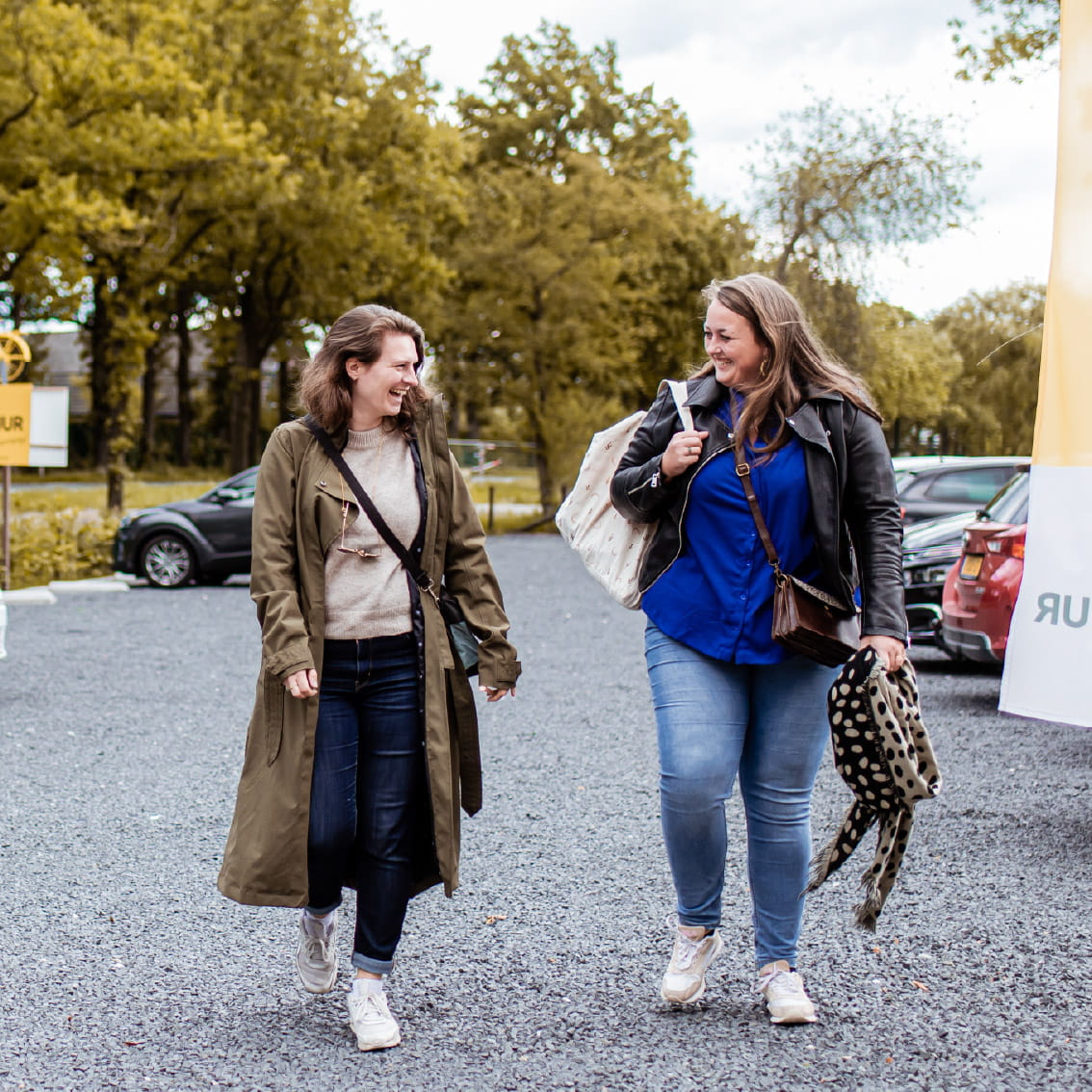 Twee deelnemers lopen lachend naar een groepsactiviteit bij Er Was Eens Woudenberg op de Utrechtse Heuvelrug.