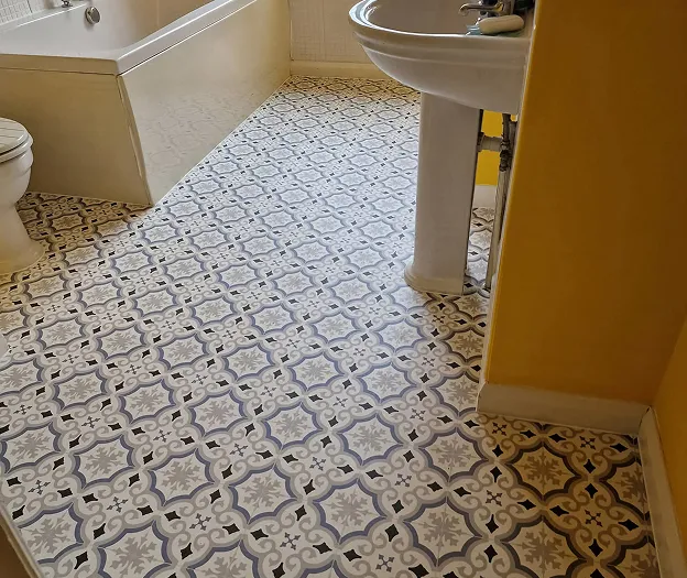 A bathroom with a sink, toilet and bathtub and patterned flooring.