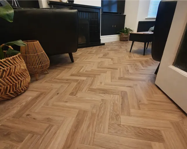 A living room with a wooden floor and black chairs.