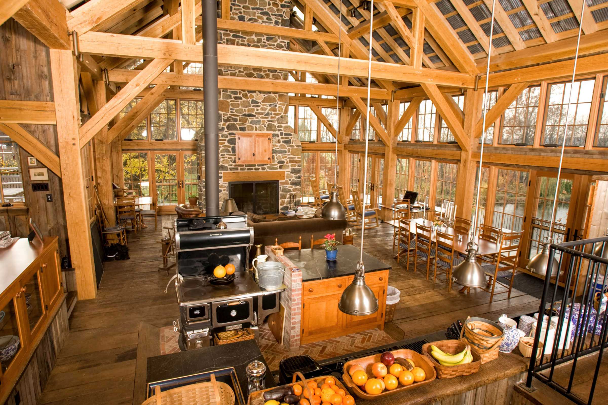 Kitchen and living room in the great room of a timber frame barn house .