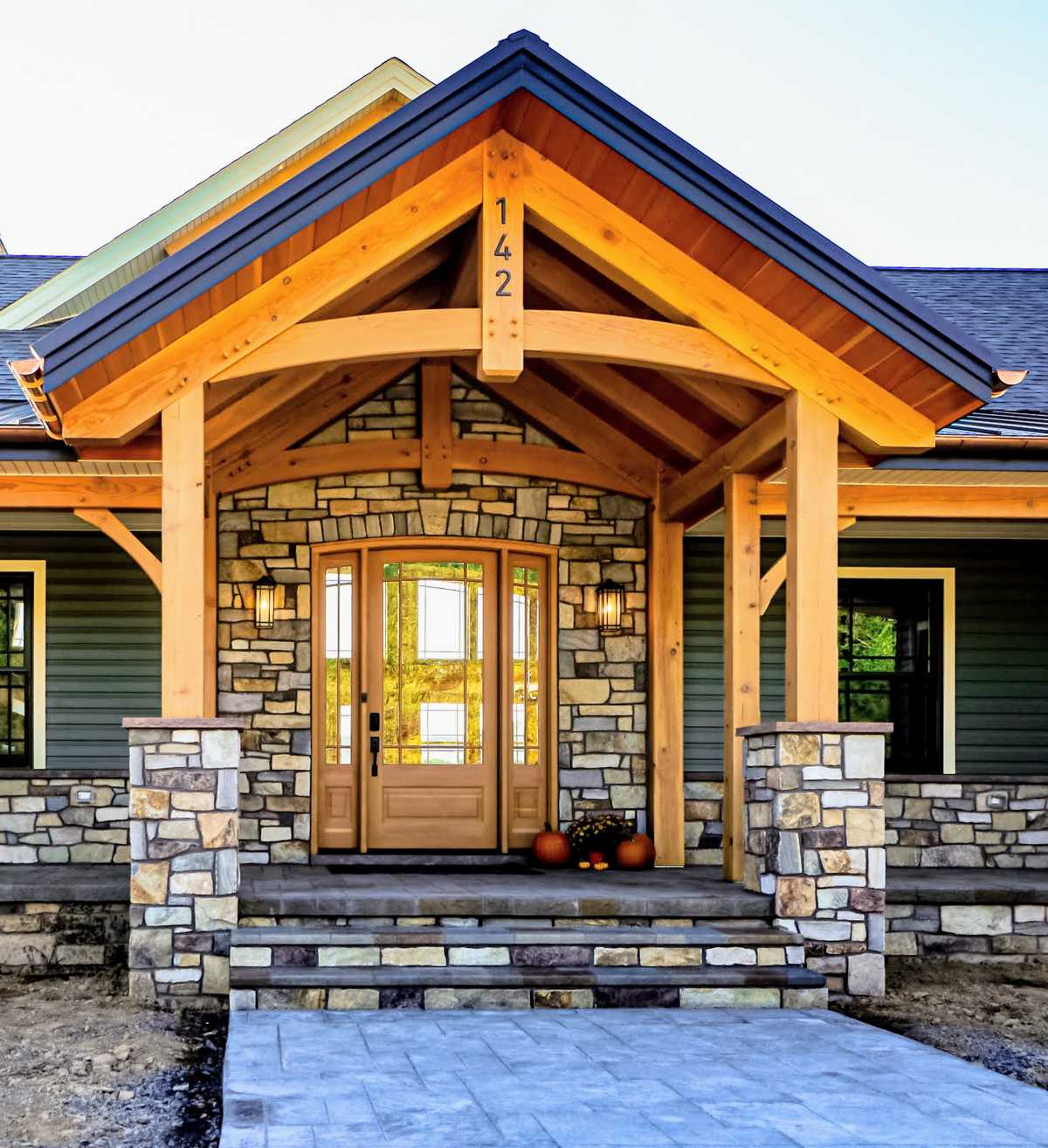 Front door with timber frame arch and stone pillars.