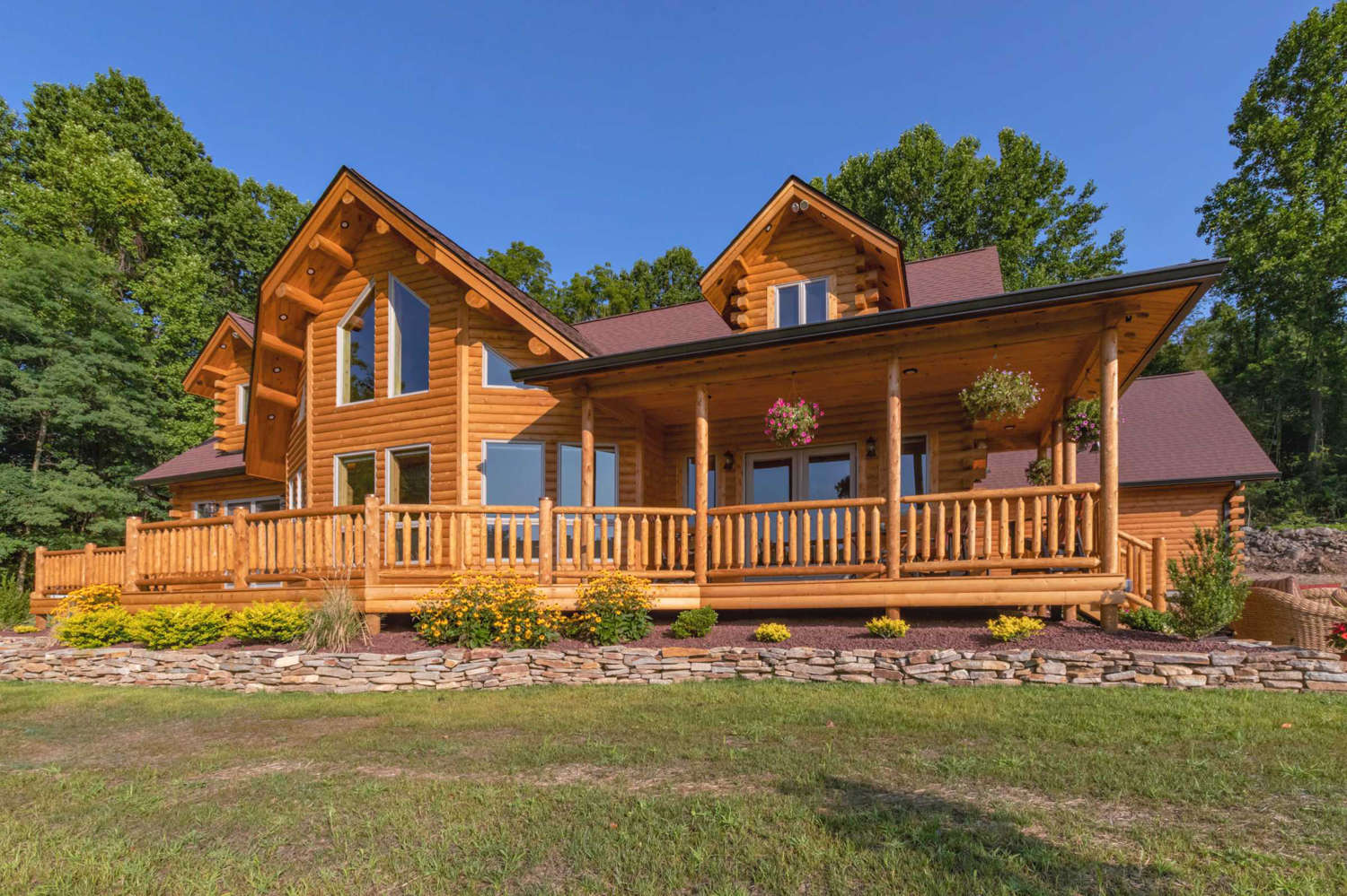 Luxury log home with front deck of natural white cedar deck boards and rustic railing.