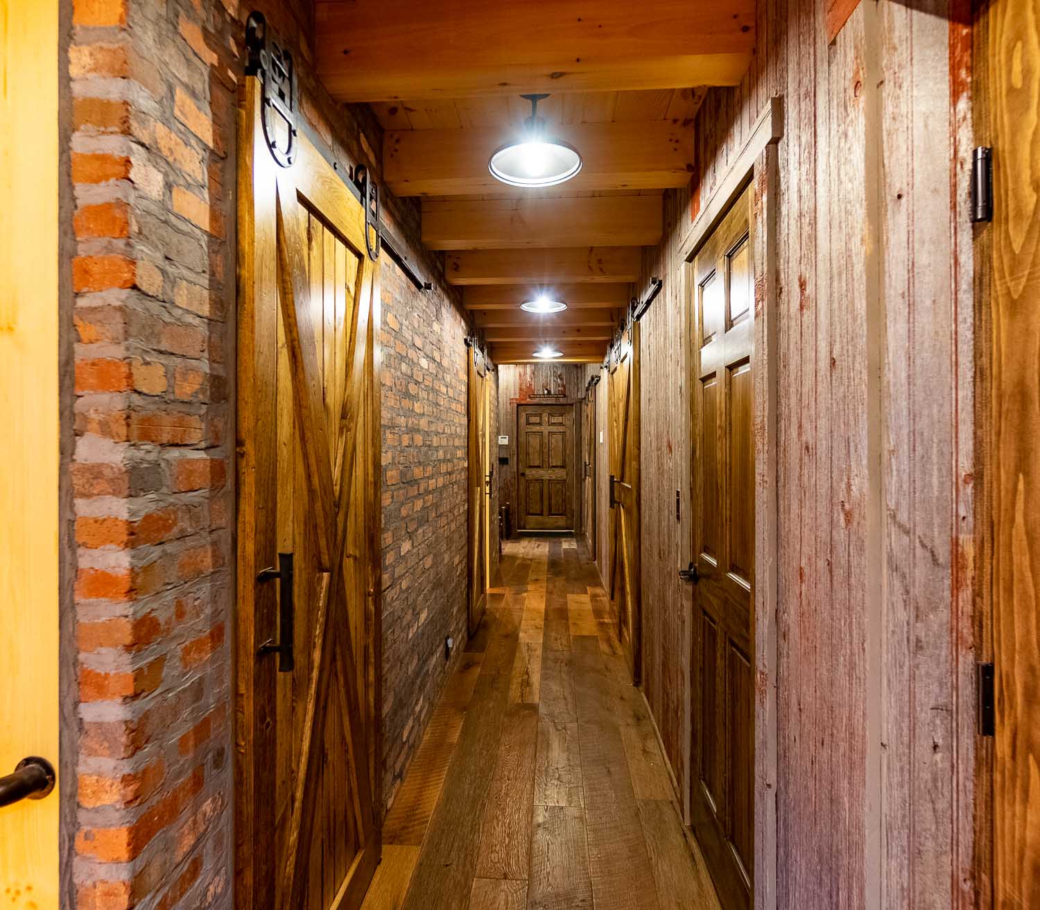 Rustic hallway with sliding barn doors, reclaimed barn siding and brick