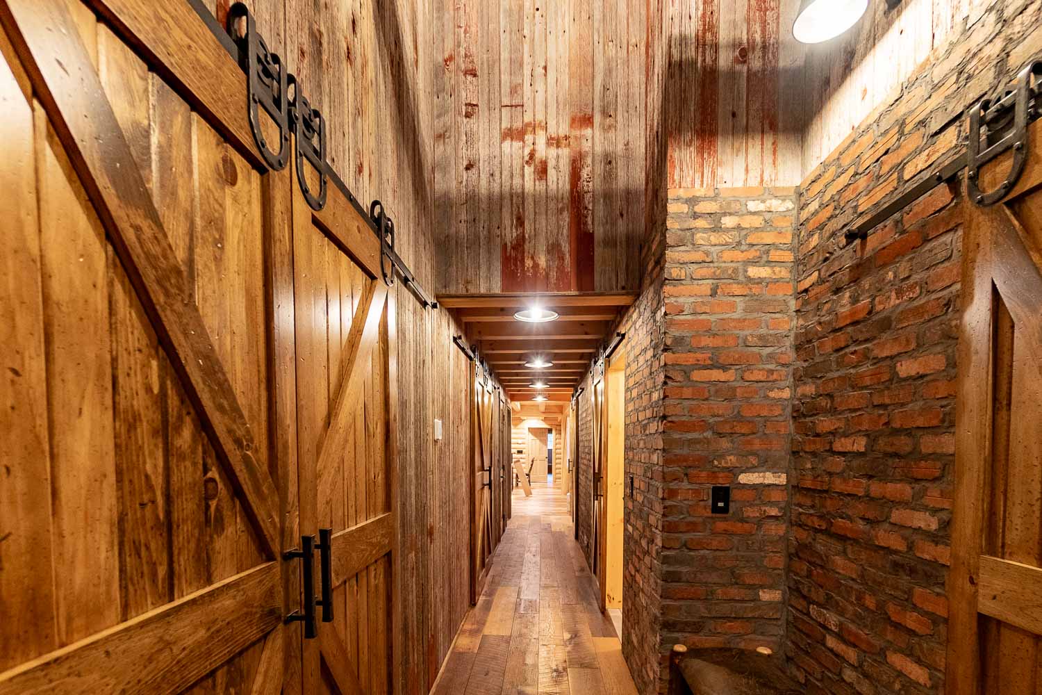 rustic hallway with sliding barn doors, reclaimed barn siding and brick