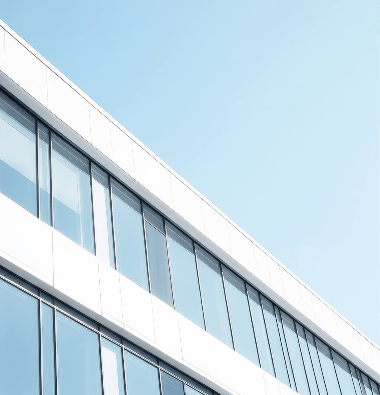 Modern building facade with large reflective glass windows under a clear blue sky.