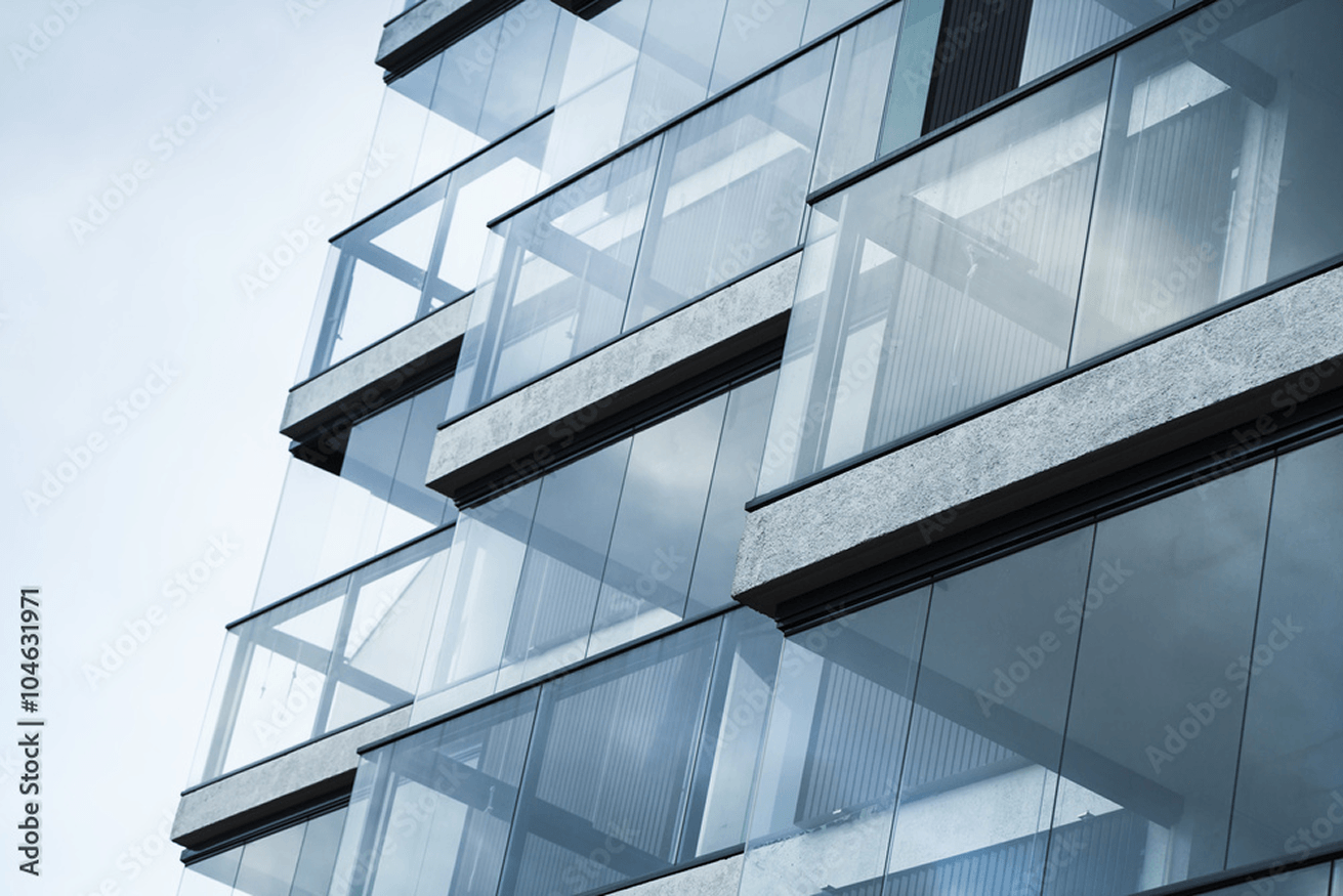 Close-up of modern building facade with glass balconies and reflective windows.