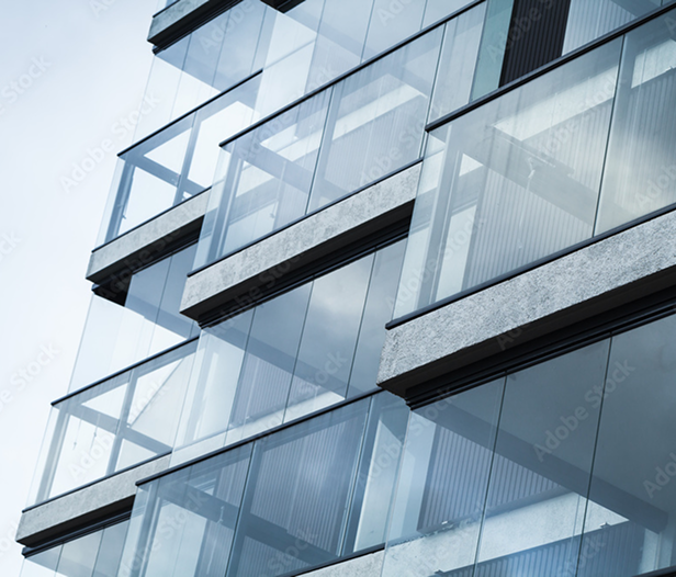 Close-up of a modern building facade with glass balconies and concrete beams.
