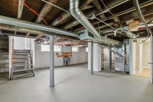 Before — gutted basement with exposed framing and plumbing — Manzil