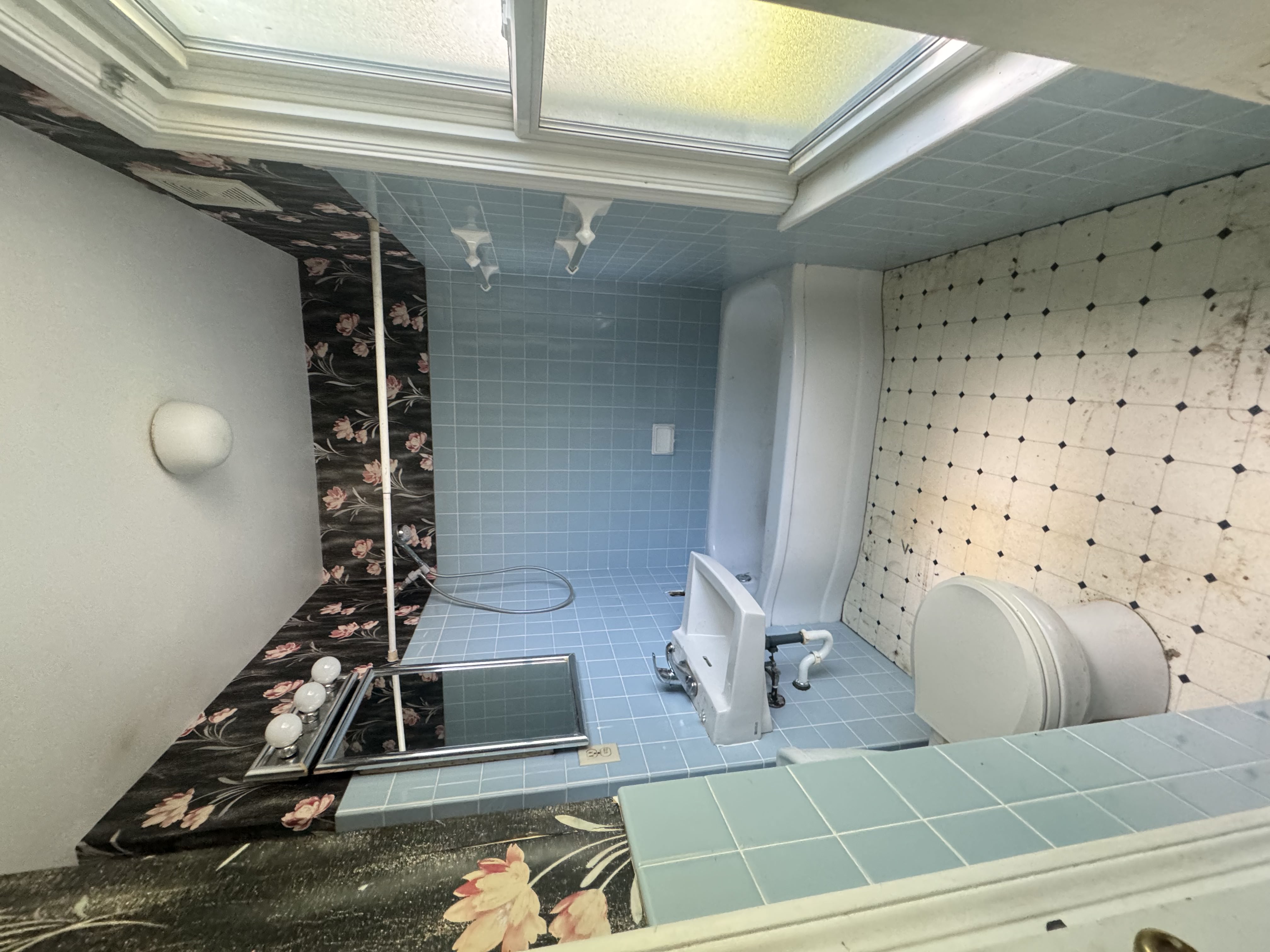 Before — blue-tile bathroom with floral wallpaper in Brecksville, OH — Manzil Renovation