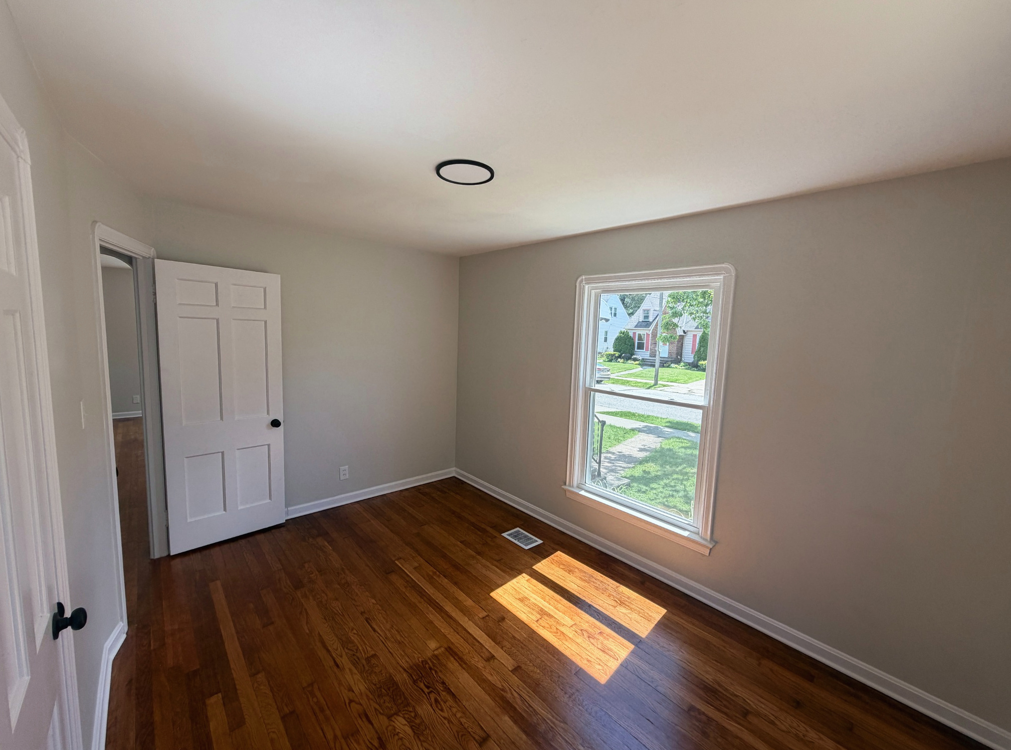 Sunlit bedroom with refinished hardwood floors and new window trim, Wayland Ave Cleveland renovation