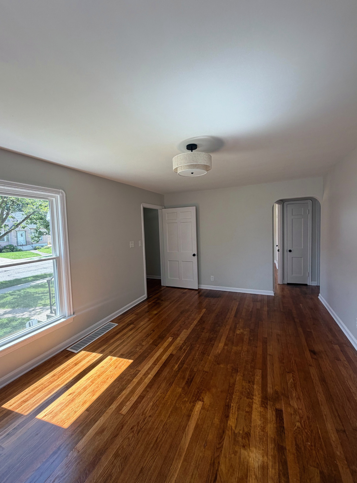Bedroom with refinished hardwood floors and new ceiling light, Wayland Ave Cleveland renovation