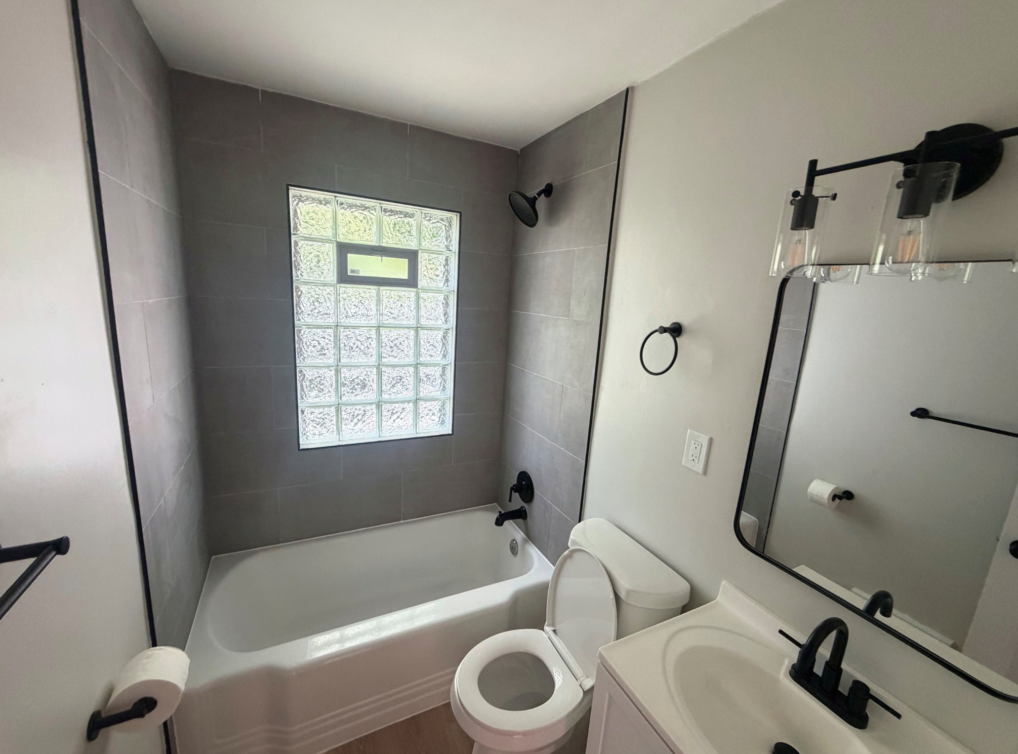 Remodeled bathroom with tub, matte black fixtures and glass-block window, Wayland Ave Cleveland renovation