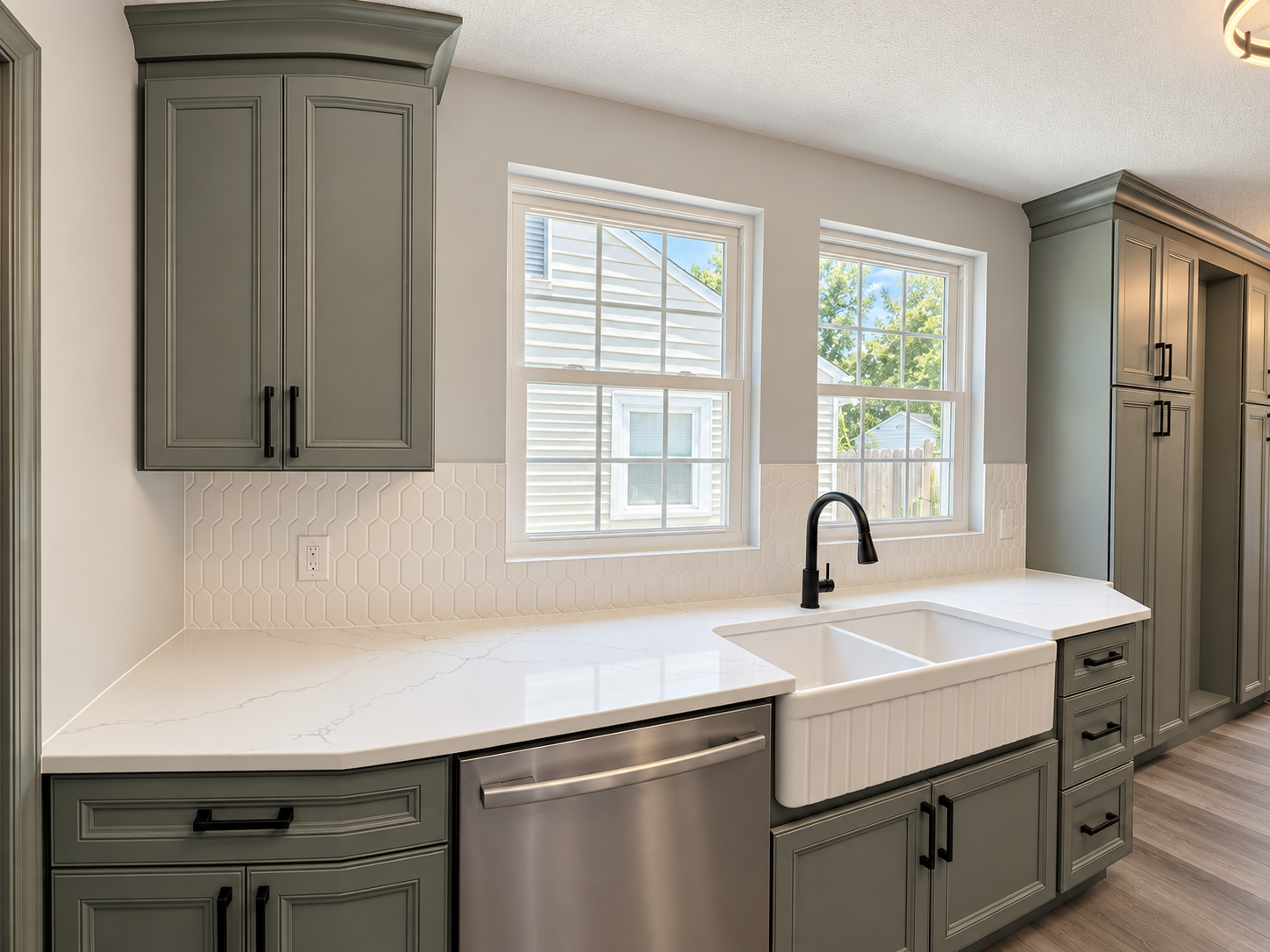White quartz counter, stainless dishwasher and black faucet by the window in a Cleveland kitchen remodel