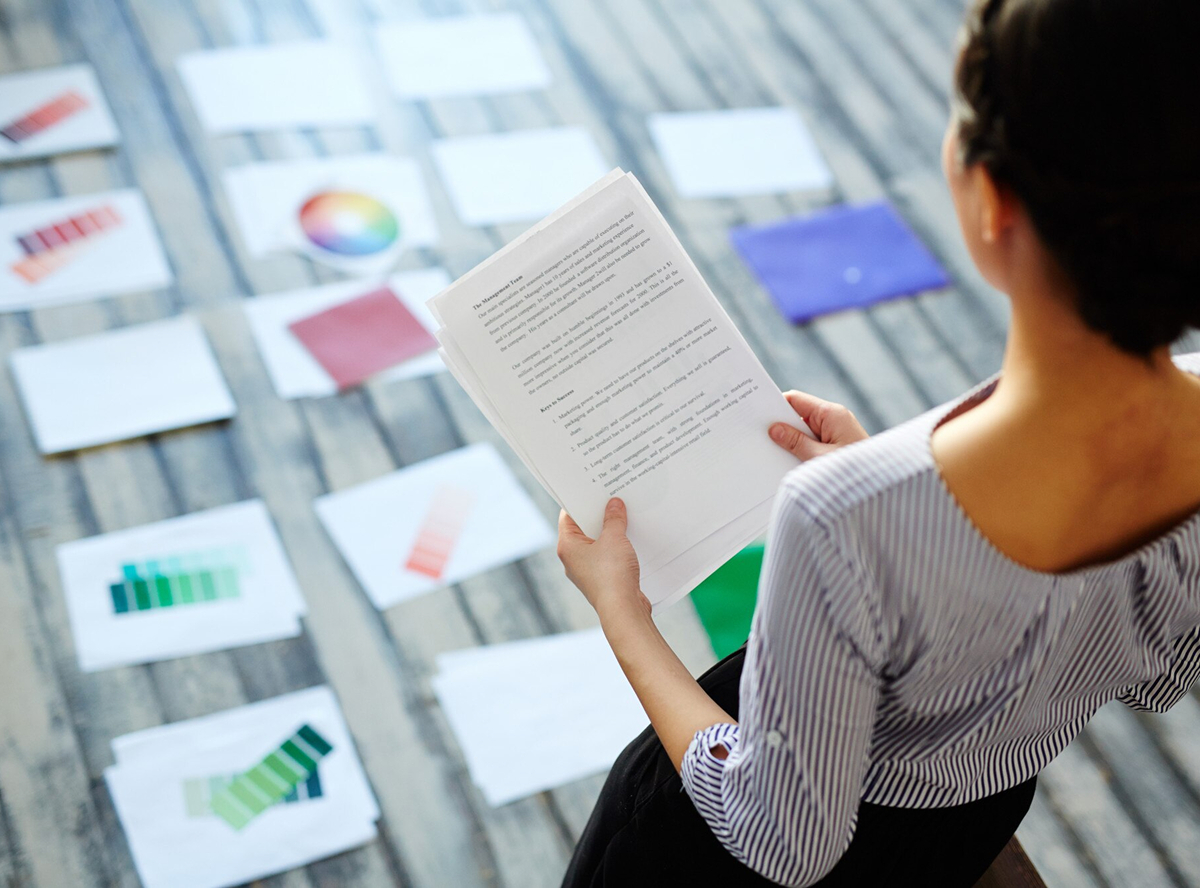 A woman holds a piece of paper displaying another piece of paper on it, showcasing a layered document presentation.