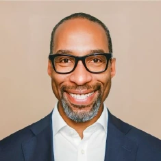 Man in glasses and in a blue coat.
