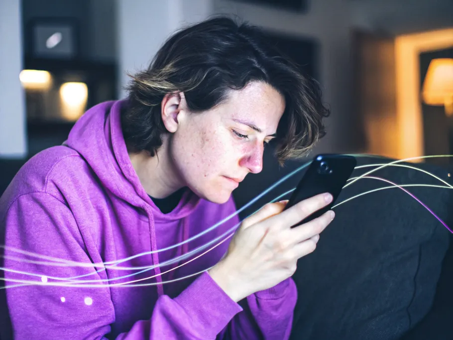 A thoughtful individual in a purple hoodie closely examining their smartphone, deep in contemplation about social media.