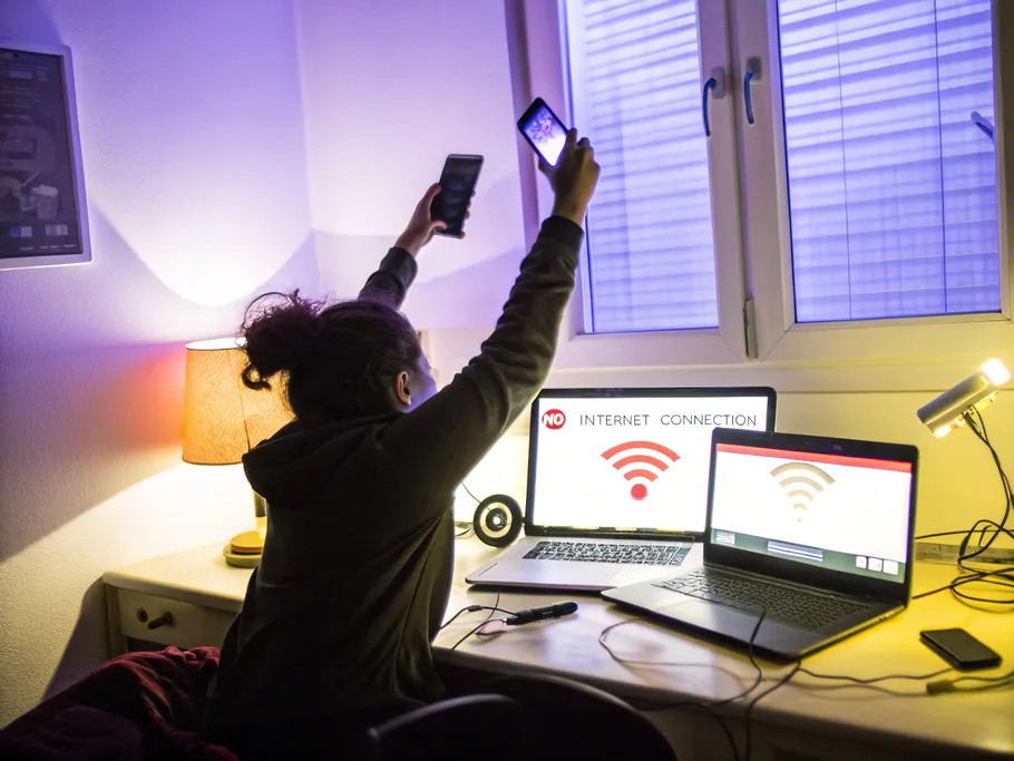 A person holding their phone high in a dimly lit room filled with devices showing no internet connection.