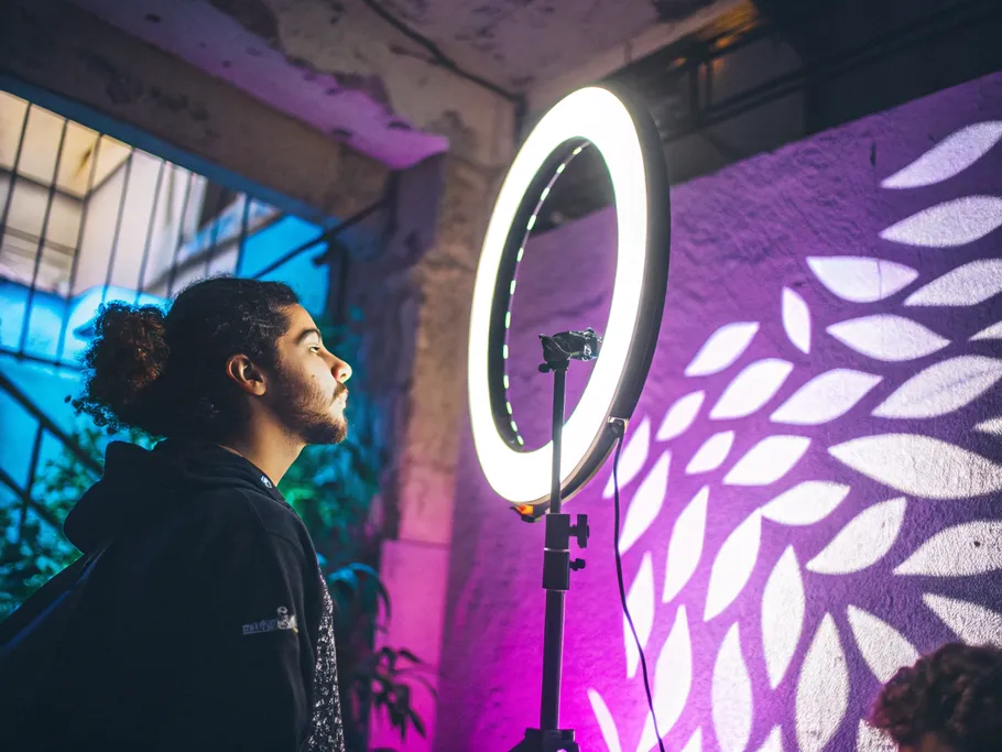 Artistic shot of a modern ring light with a flexible neck casting soft, diffused illumination on a textured wall.