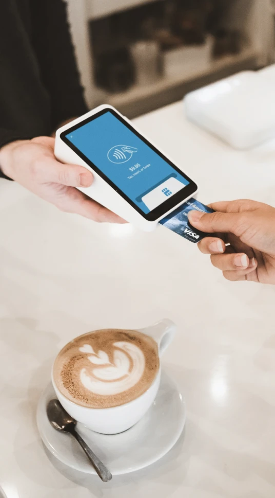 Person paying for coffee with a credit card on a mobile payment device