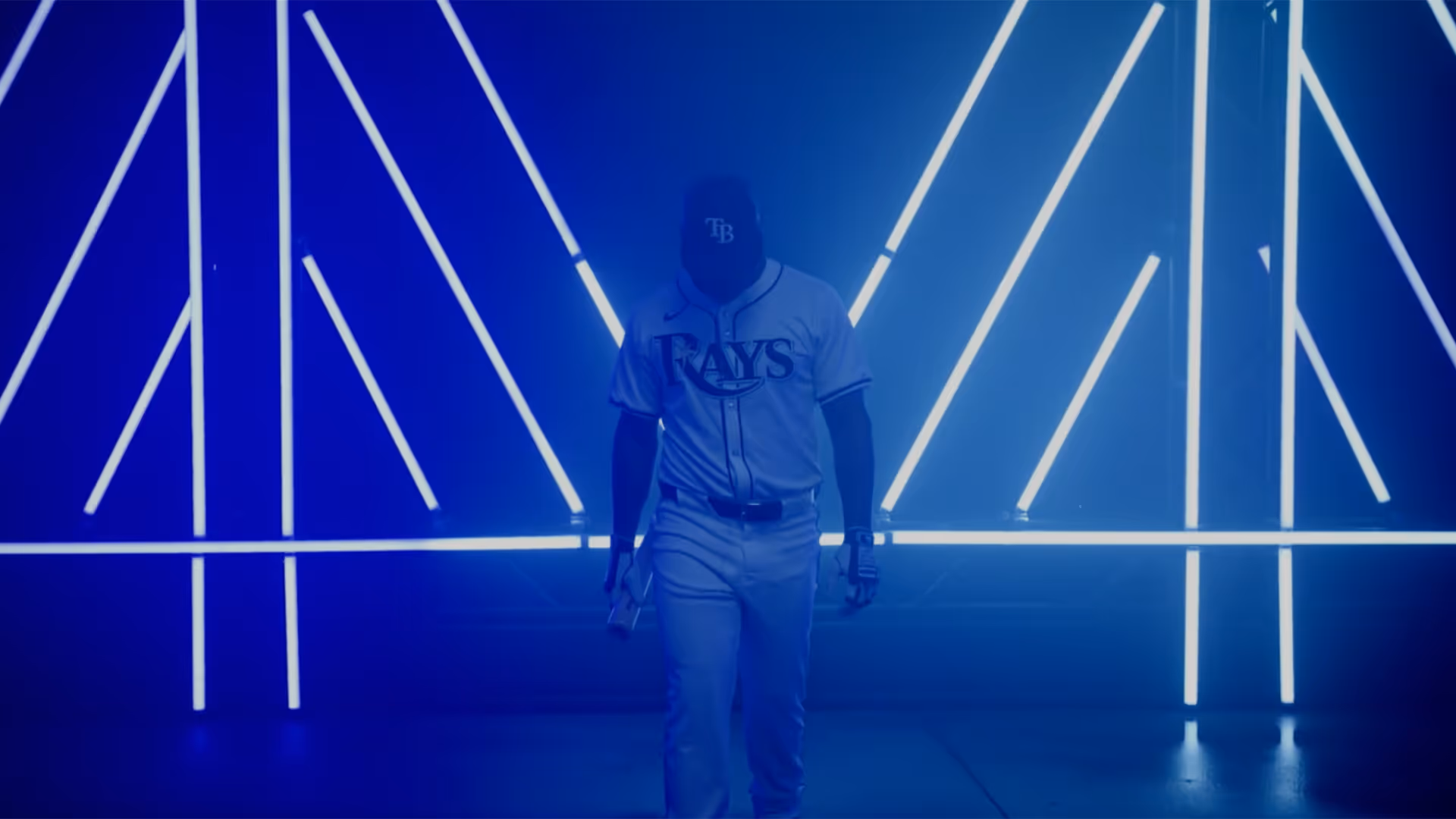 Baseball player wearing Tampa Bay Rays uniform walking forward with glowing white light tubes in the background.