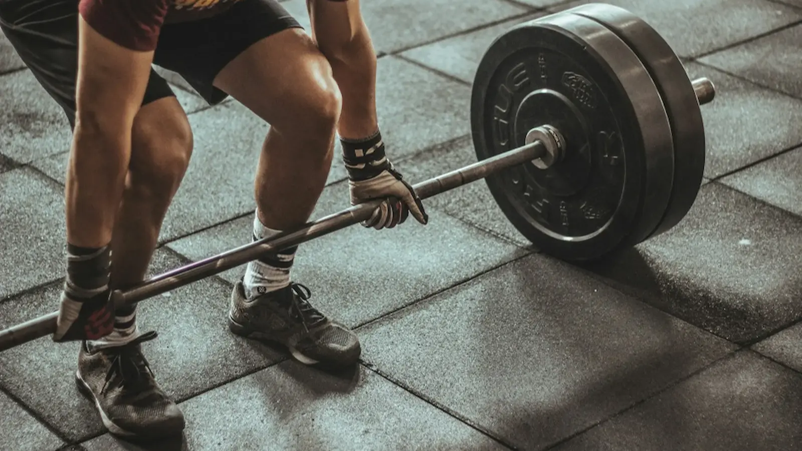 A person squatting with a bar and barbell weights.
