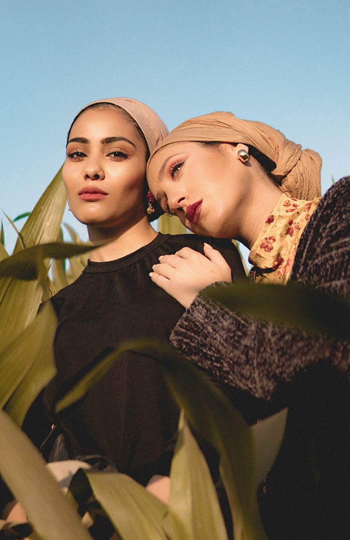 Two women are standing in a corn field