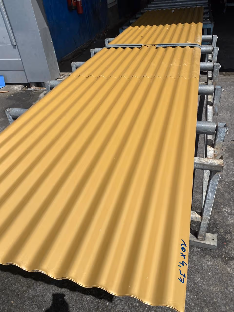 Feuille ondulée jaune posée sur un support métallique dans un environnement industriel.