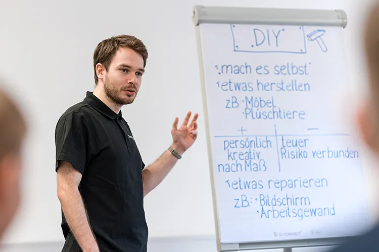 Lehrling übt selbstbewusstes Präsentieren am Flipchart während eines professionellen Präsentationstrainings.