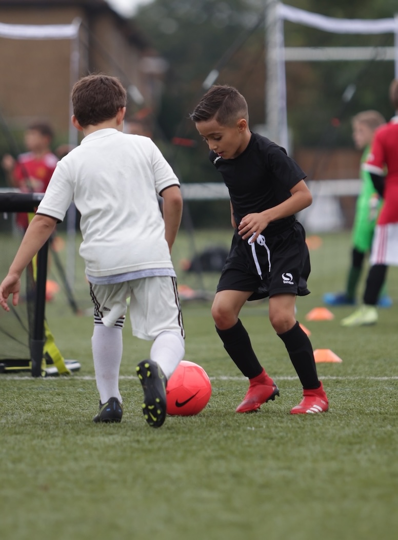 Two children playing football together outdoors
