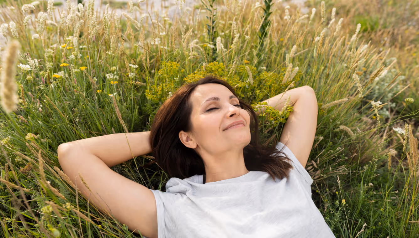 A woman lying in a field of grass, looking relaxed and content.