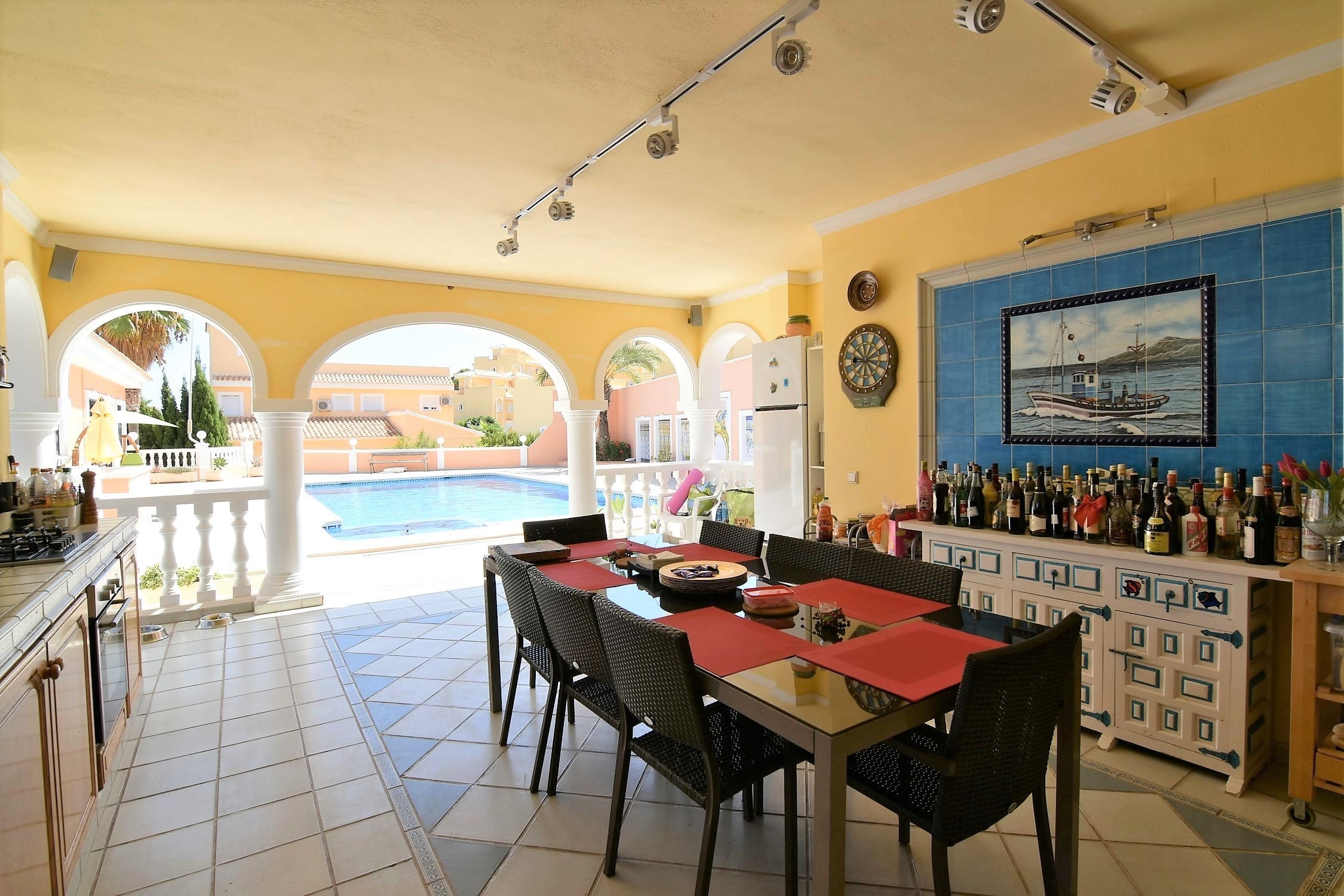 Spacious summer kitchen with a dining area looking out to the swimming pool through classic arches.