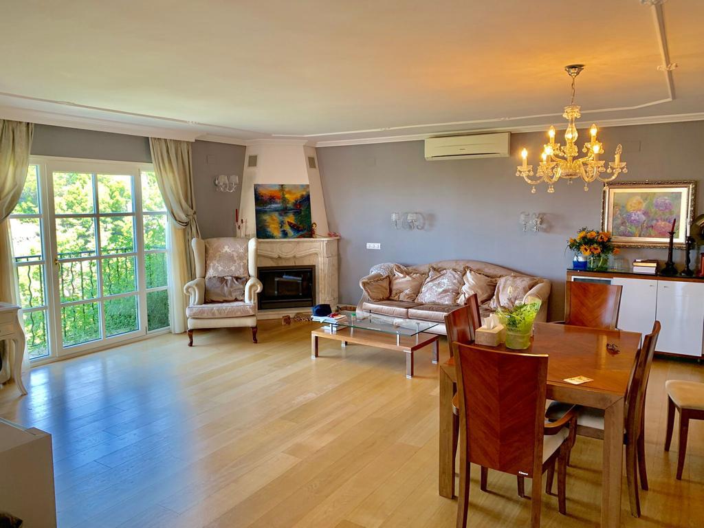 Elegant living and dining room with hardwood floors and a classic fireplace.