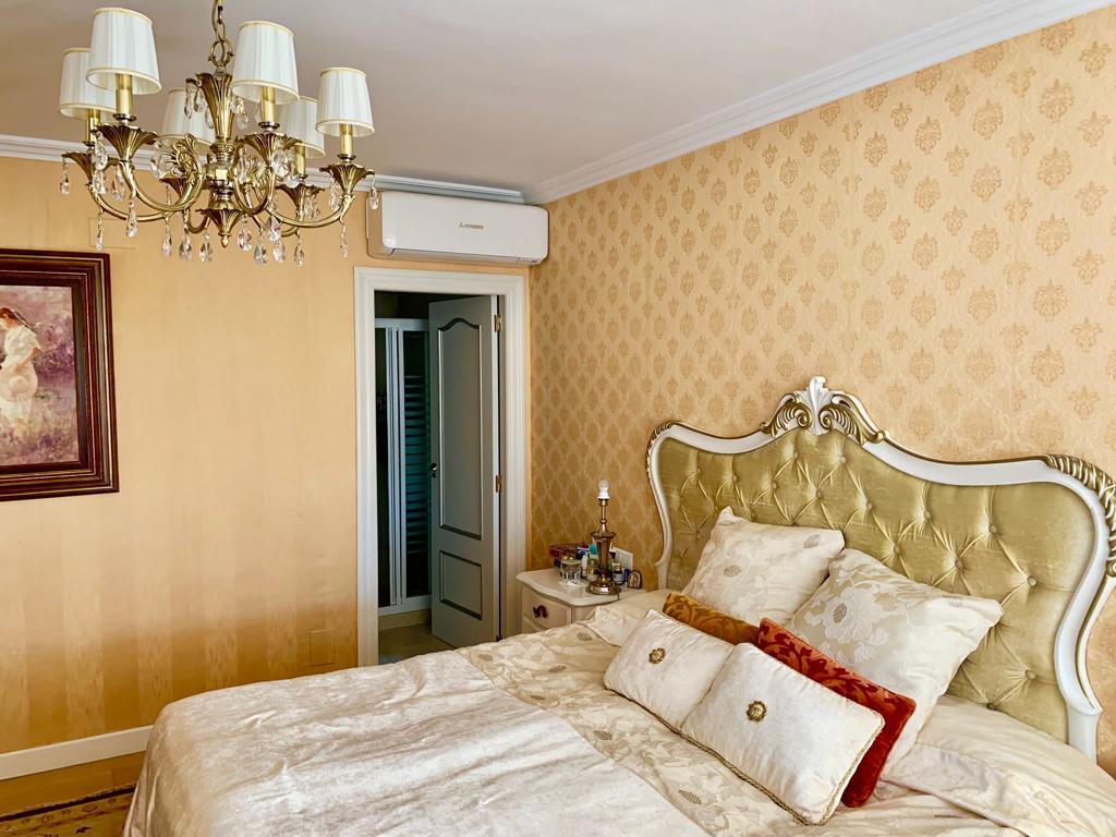Luxurious primary bedroom with damask wallpaper and an en-suite bathroom.