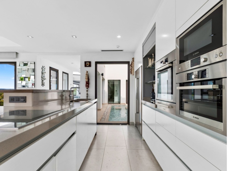Gourmet kitchen with premium Bosch appliances in luxury villa for sale - white cabinets and pool views