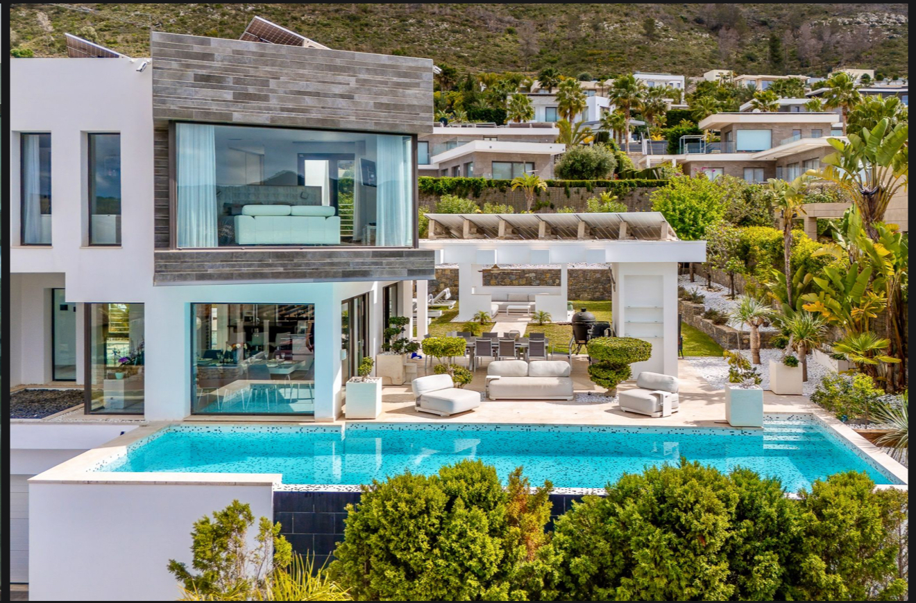 Front facade of Luxury Seafront Villa with modern architecture, large glass panels, and Mediterranean backdrop.