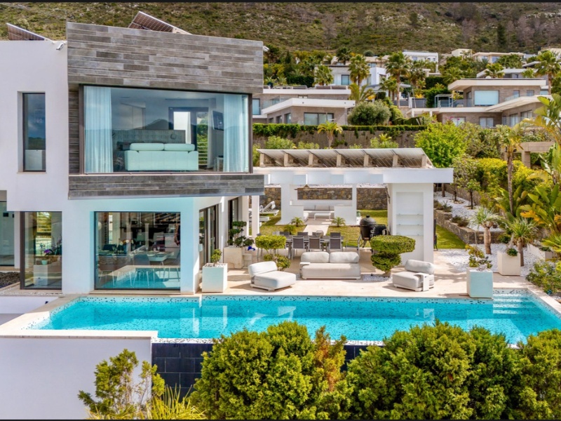 Main swimming pool with outdoor terrace in luxury seafront villa - premium lounging area and mountain backdrop