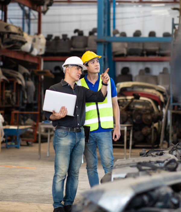 Two industrial workers in safety helmets discussing recycling operations at a facility
