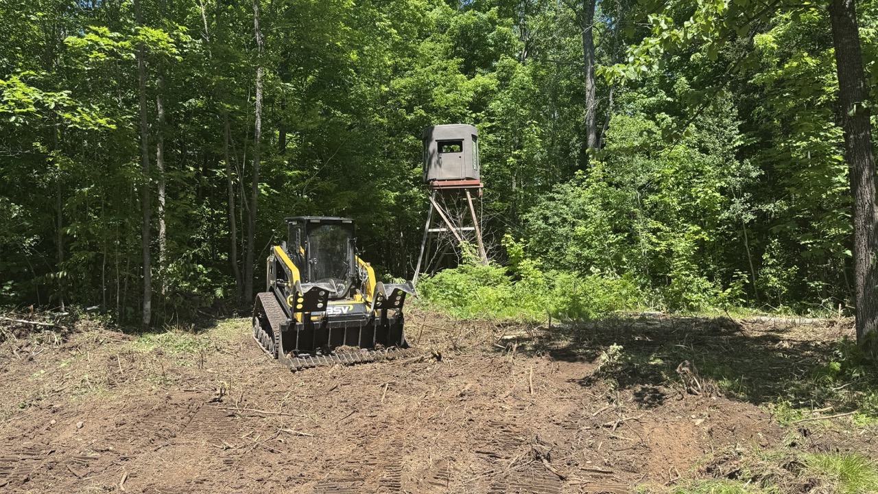 ASV tracked machine clearing a new food plot with a hunting blind in the background in Wisconsin