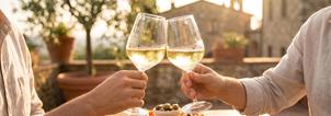 Two glasses of Luna Nuda Pinot Grigio raised in a toast at golden hour