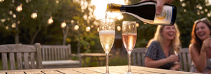 Friends clinking flutes of Luna Nuda Prosecco outdoors in celebration
