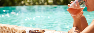 A chilled glass of Luna Nuda Rosé held poolside on a sunny afternoon